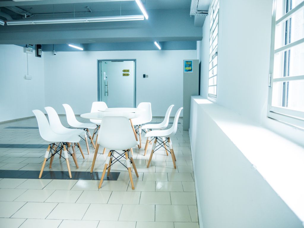 A clean and minimalistic office meeting room with white chairs and table.