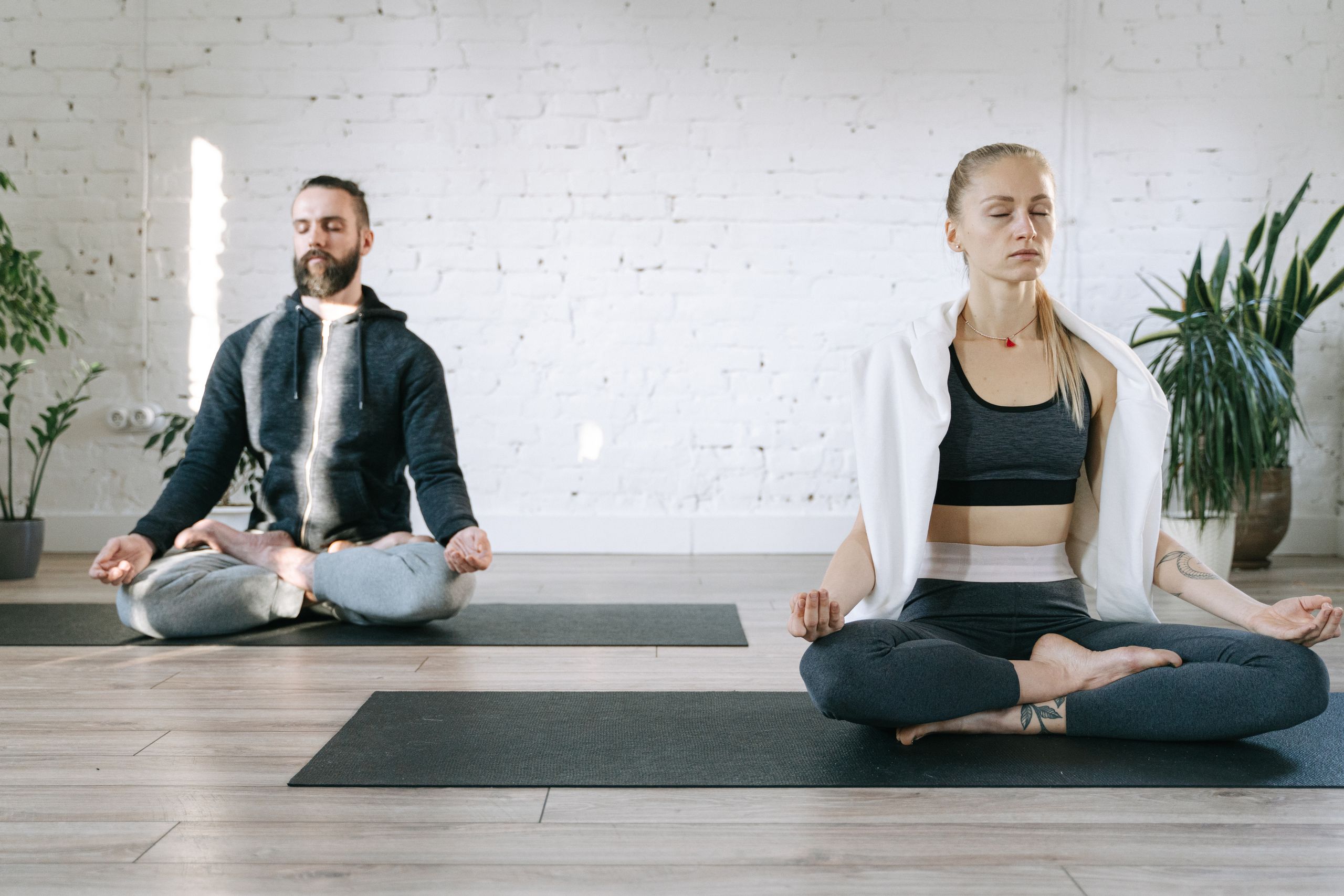 Couple meditating in lotus position in a serene room, enhancing mental peace.